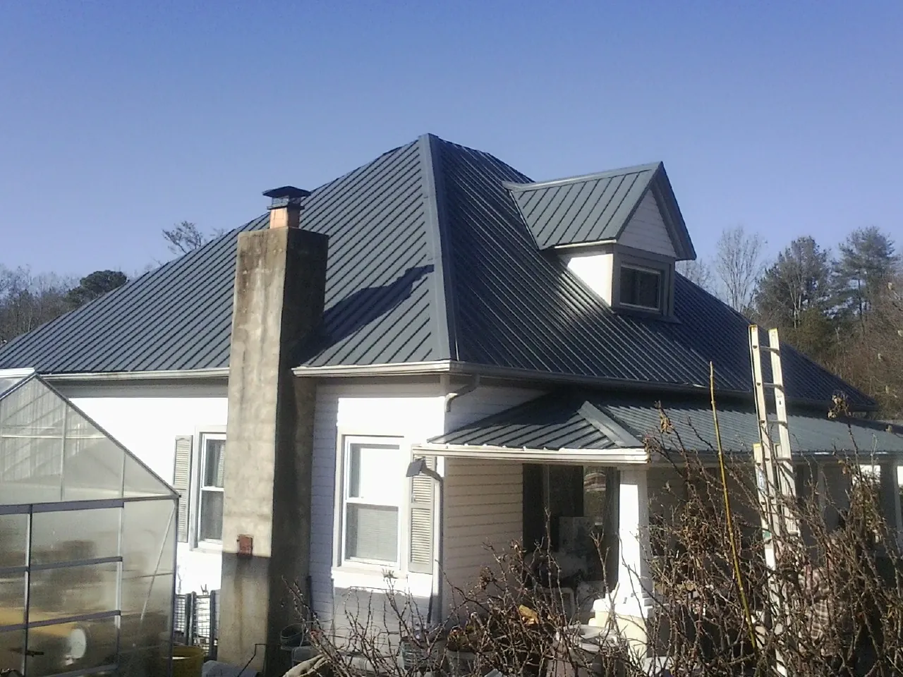 Dark blue standing seam metal roof on a white farmhouse with dormer — Slate & Tile Roof Repair by Roofing Brothers in Asheville