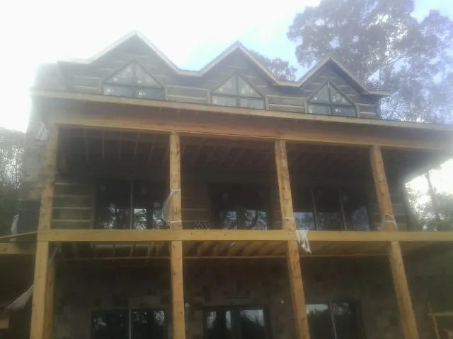 Dormers and porch framing on a large log home under construction — Roof Coating work by our crew in Asheville