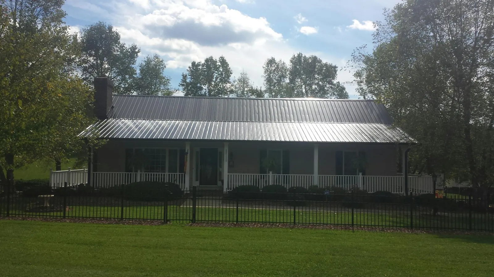 Gray metal roof on a brick ranch with a full width front porch — Gutter Guard Installation work by our crew in Asheville
