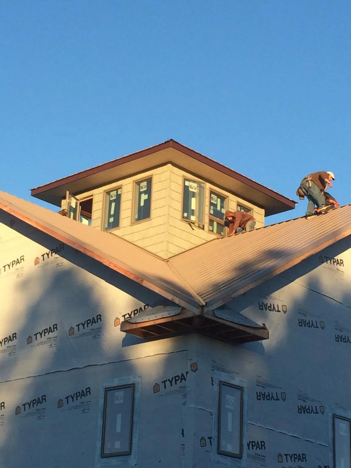 Roofers working around a rooftop cupola on a new metal roof at sunset — Roof Waterproofing in Asheville by Roofing Brothers